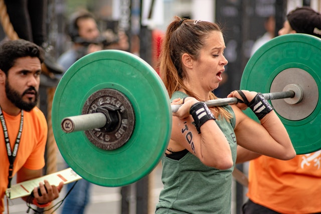Athlete lifting in a CrossFit gym with a coach judging the lift